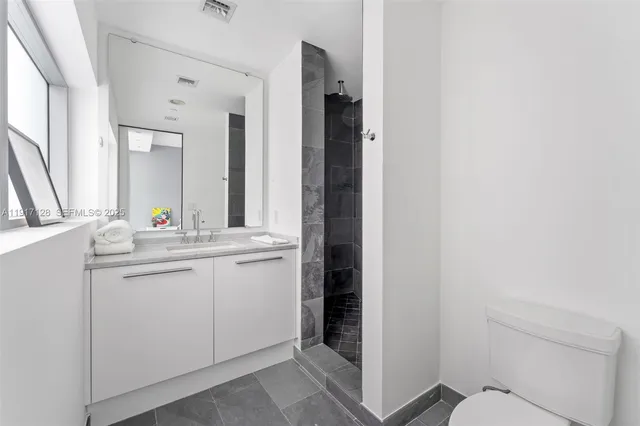 a bathroom with a granite countertop sink toilet and mirror