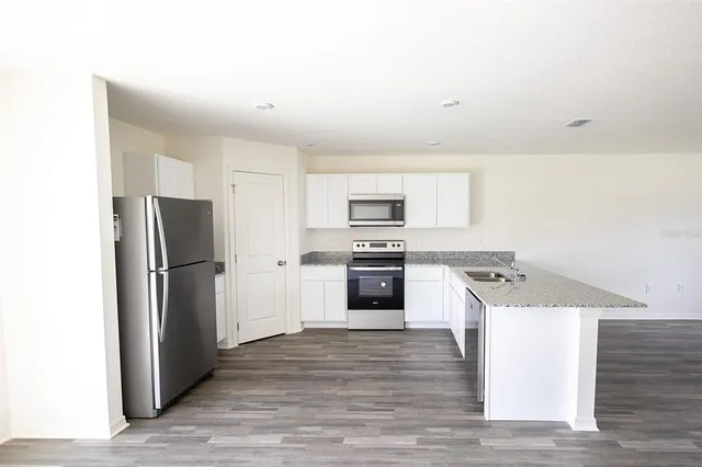 a large kitchen with kitchen island a sink dishwasher a stove and a refrigerator with wooden floor