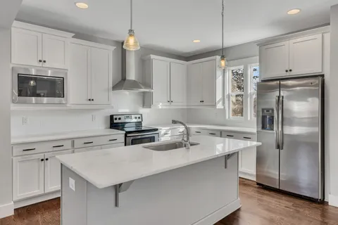 a kitchen with stainless steel appliances a sink a stove a refrigerator and cabinets