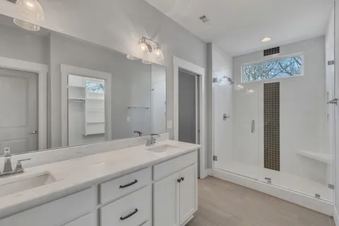 a bathroom with a double vanity sink mirror and shower