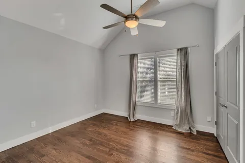 an empty room with wooden floor fan and windows