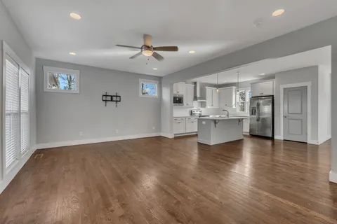 a view of an empty room with kitchen and window