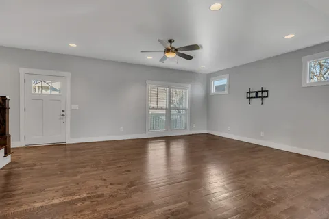 an empty room with wooden floor ceiling fan and windows