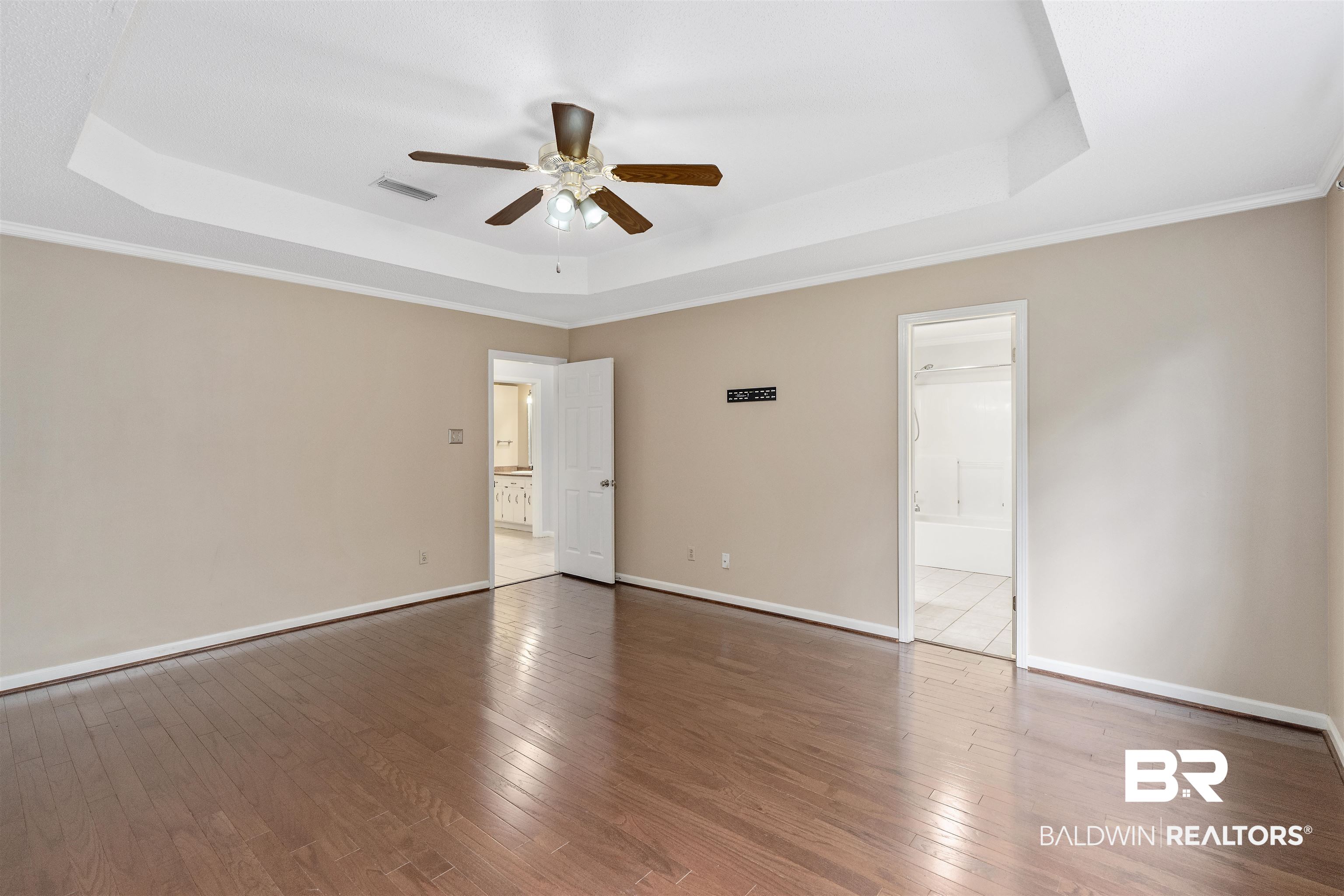 25779 Austin Road Daphne, AL 36526 - Photo 12 of 30 Unfurnished bedroom featuring a raised ceiling, hardwood / wood-style flooring, baseboards, ensuite bath, and crown molding