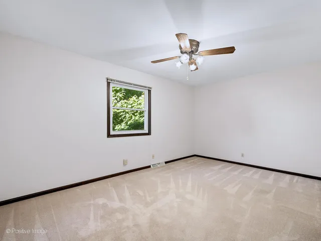 an empty room with windows and ceiling fan