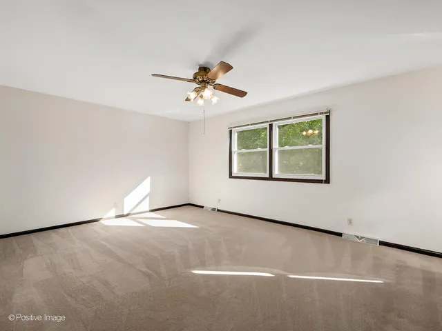 an empty room with windows and ceiling fan