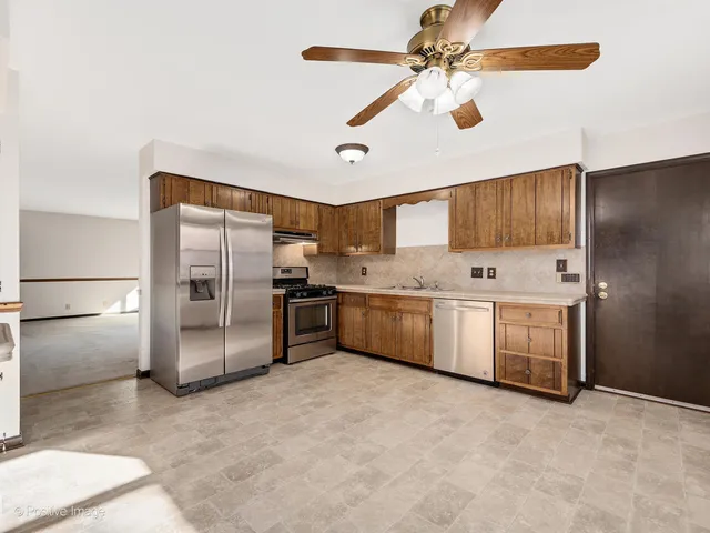 a kitchen with stainless steel appliances a refrigerator a sink and white cabinets