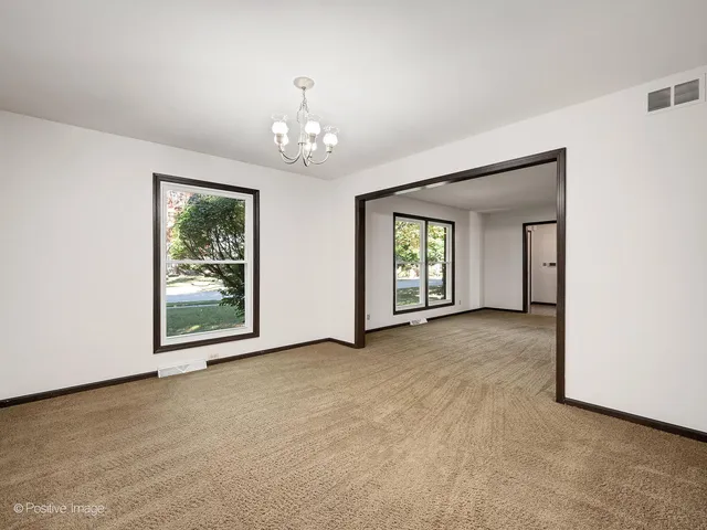 an empty room with windows and chandelier