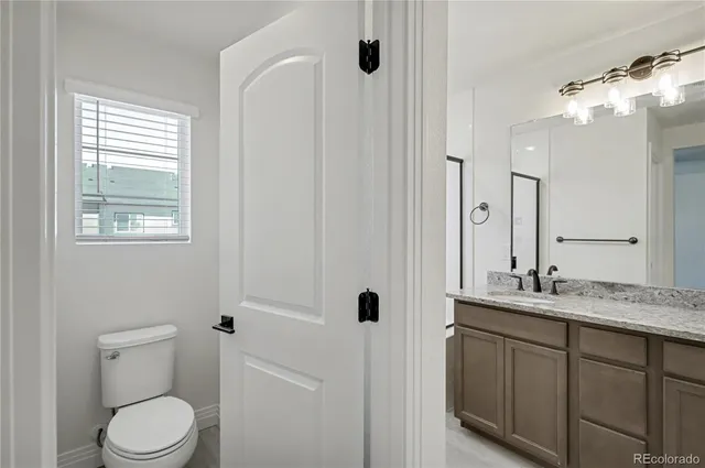 a bathroom with a granite countertop sink toilet and mirror