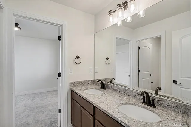 a bathroom with a granite countertop double vanity sink and a mirror