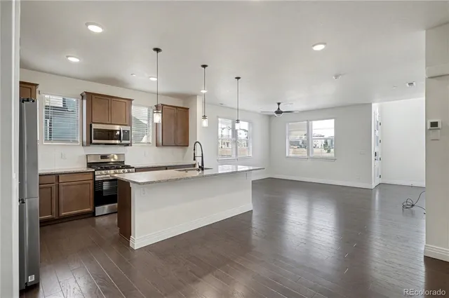 a large kitchen with stainless steel appliances granite countertop a stove and a wooden floors