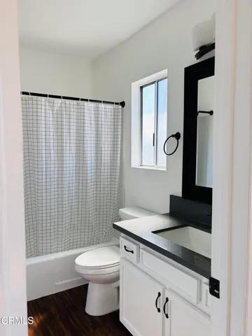 a bathroom with a granite countertop bathtub sink vanity mirror and toilet