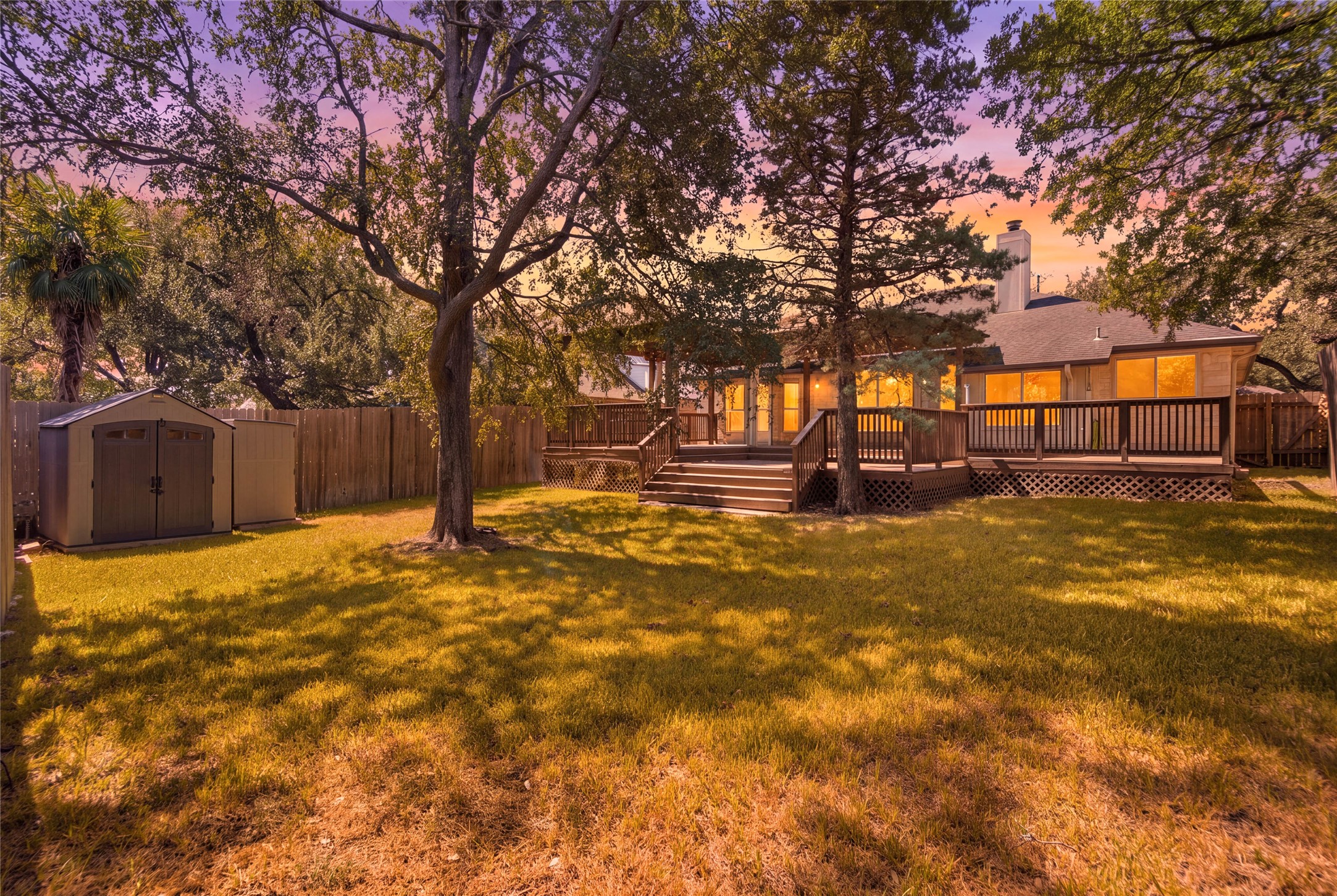 6032 Roxbury Lane Austin, TX 78739 - Photo 33 of 34 Mature trees shade a spacious lawn featuring an elevated wooden deck and detached storage shed.