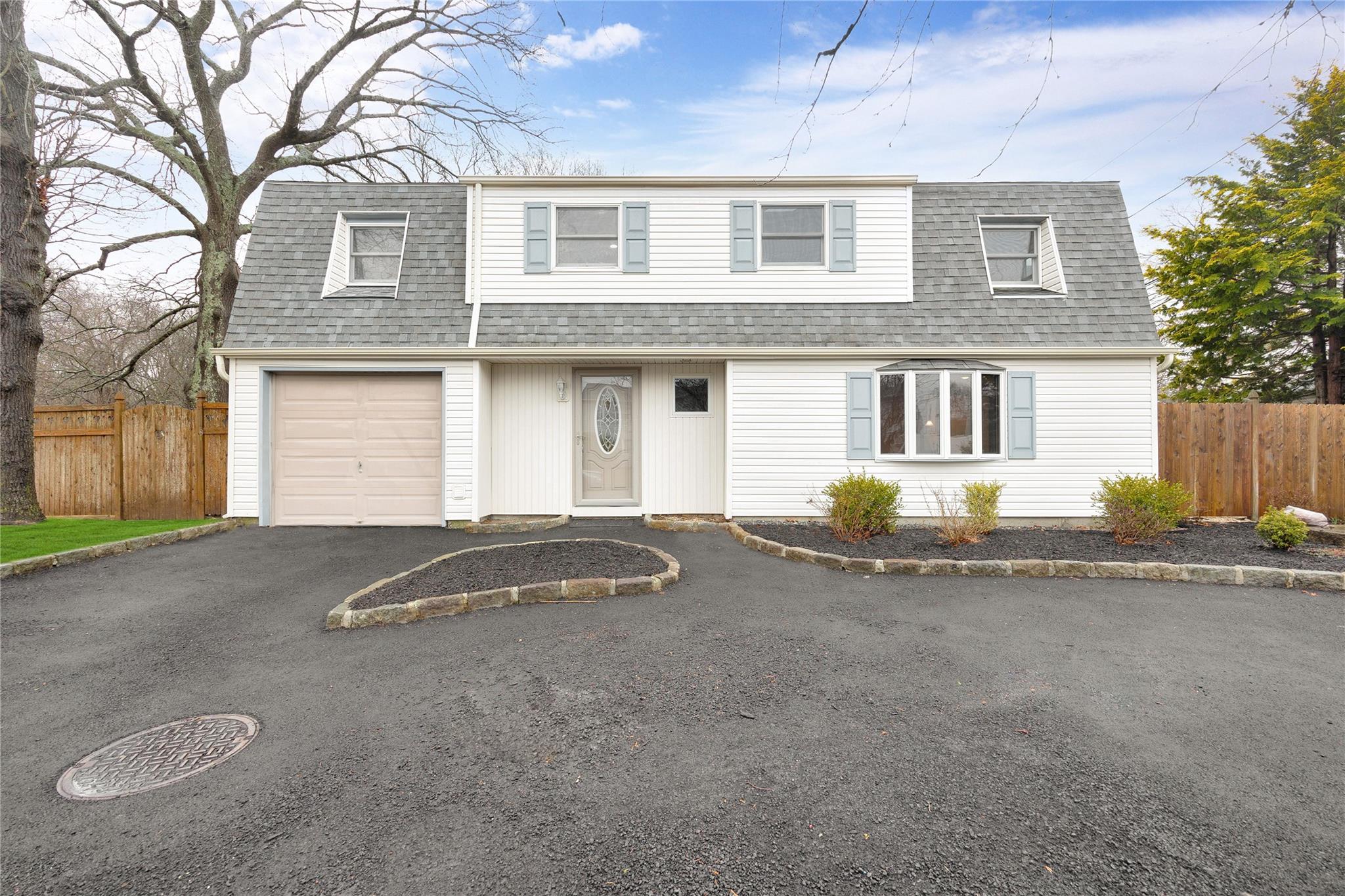 View of front of property featuring a gambrel roof, fence, a garage, and roof with shingles
