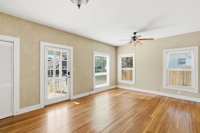 a view of an empty room with window and wooden floor