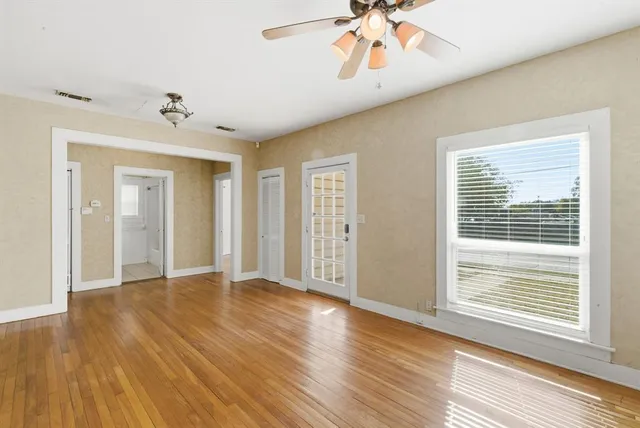 a view of an empty room with wooden floor and a window