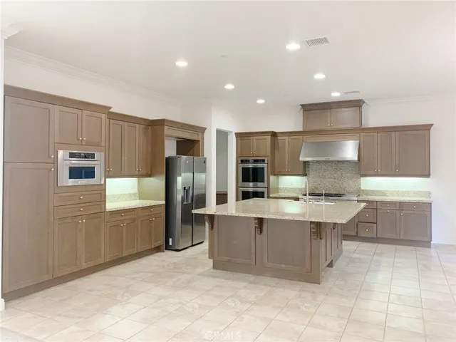 a large kitchen with kitchen island a sink a stove a refrigerator and white cabinets