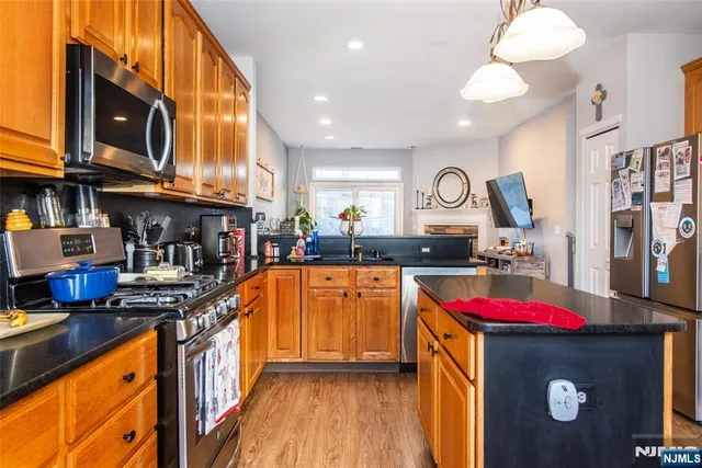 a kitchen with granite countertop lots of stainless steel appliances granite countertop a stove a sink dishwasher and cabinets with wooden floor