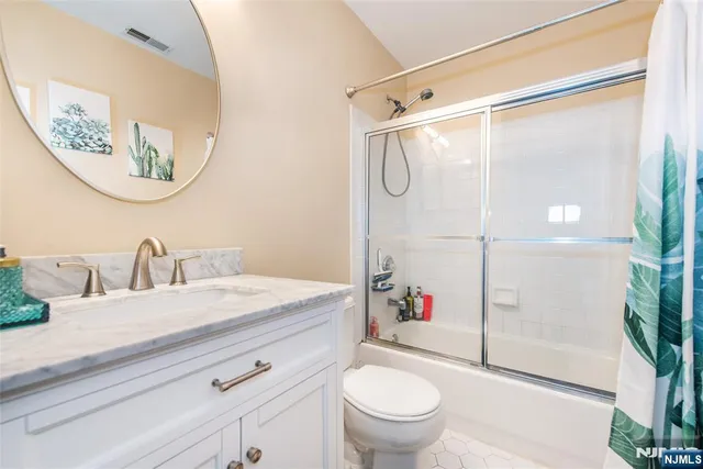 a bathroom with a granite countertop sink mirror vanity and toilet