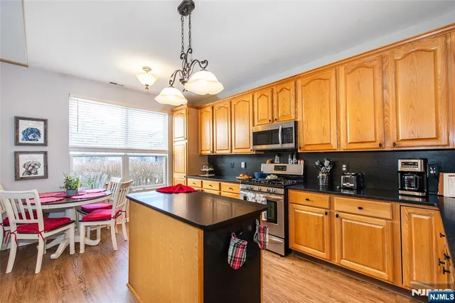 a kitchen with stainless steel appliances granite countertop a stove a sink dishwasher a dining table and chairs with wooden floor