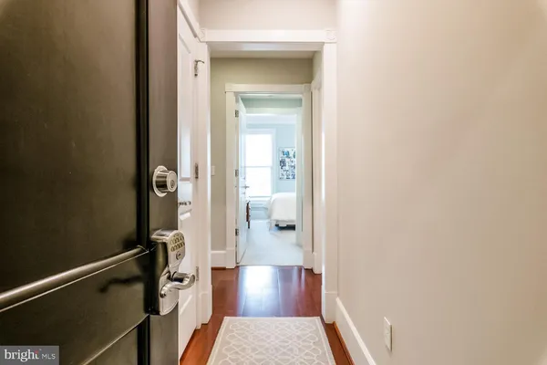 a view of a hallway with wooden floor and a bathroom