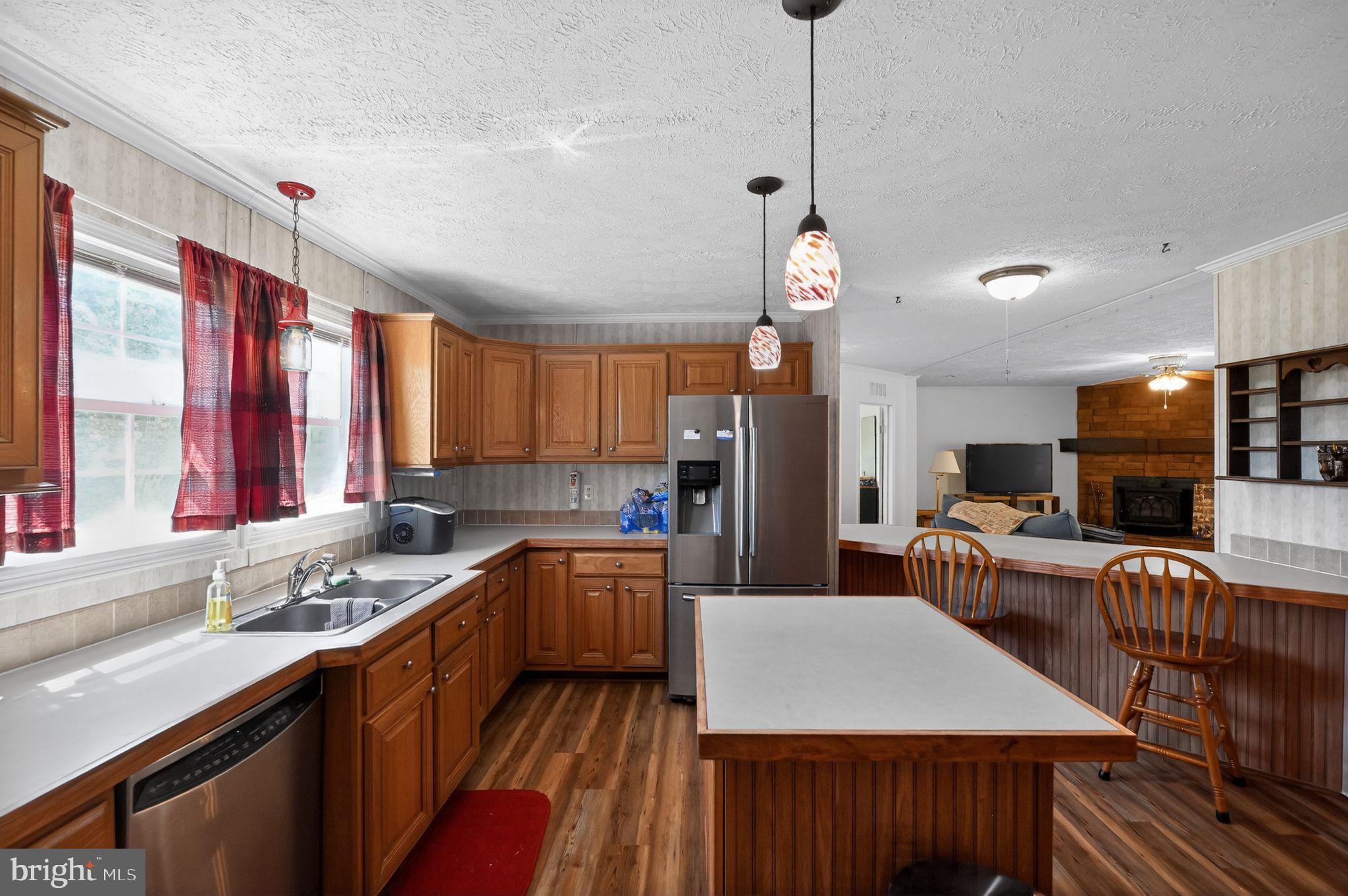 178 Lizzie Mills Road Castleton, VA 22716 - Photo 30 of 40 a kitchen with stainless steel appliances kitchen island granite countertop a sink dishwasher a stove a refrigerator a microwave oven with a dining table and chairs with wooden floor