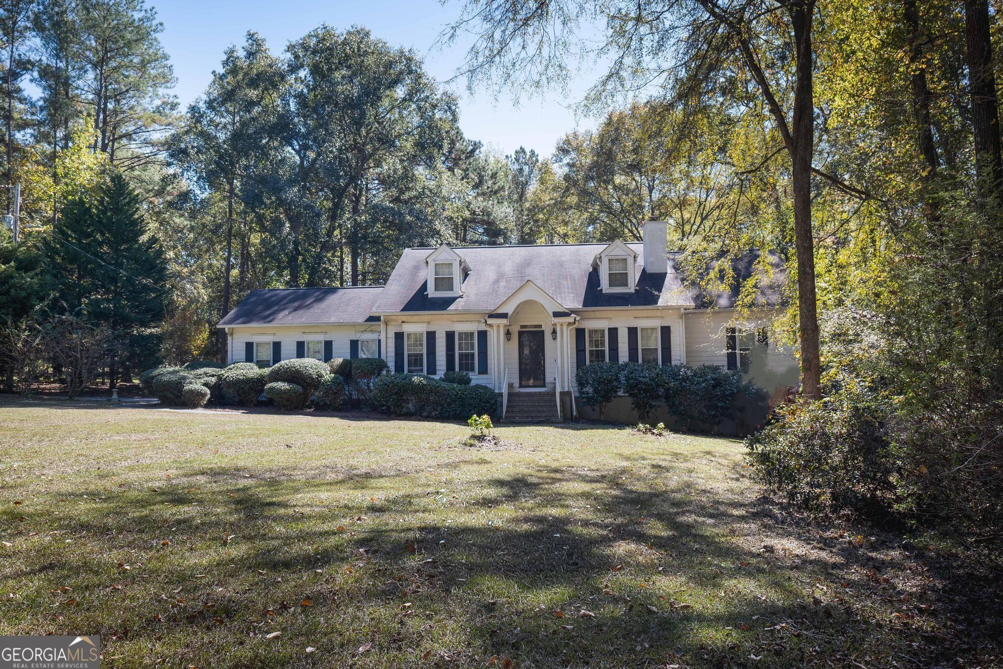 a front view of a house with a yard covered with snow and trees