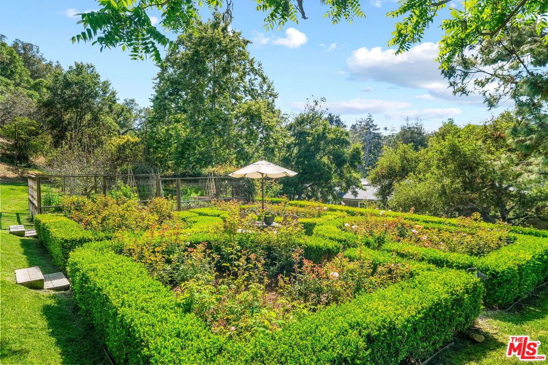 14100 Rustic Lane Pacific Palisades, CA 90272 - Photo 39 of 46 a view of a garden with lawn chairs under an umbrella