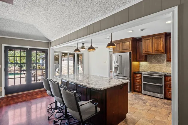 a kitchen with stainless steel appliances granite countertop a refrigerator a stove and a sink