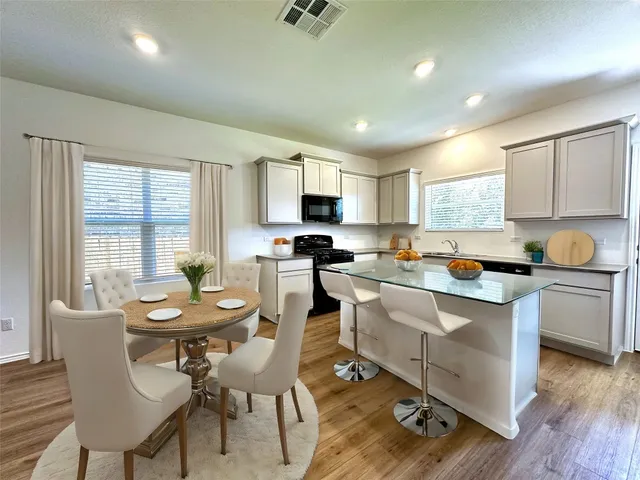 a kitchen with a dining table chairs and refrigerator