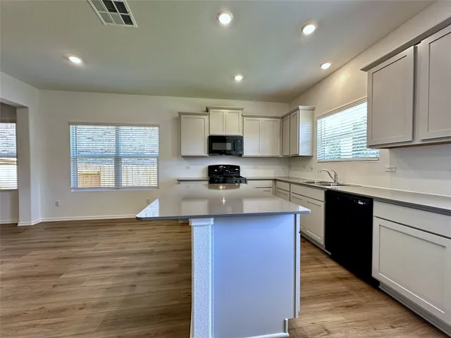 a kitchen with granite countertop a stove a sink and a microwave