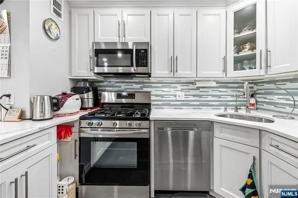 a kitchen with granite countertop a stove top oven microwave and cabinets