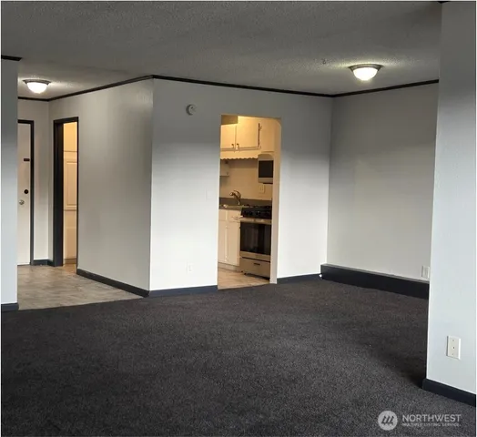 a view of an empty room with kitchen and a window