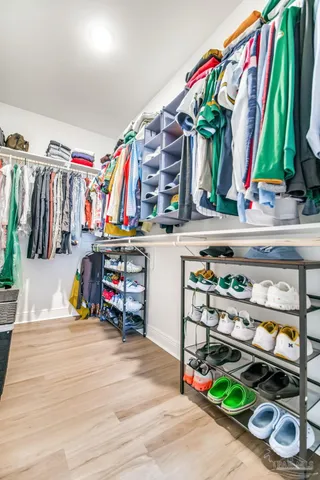 a view of walk in closet with clothes and shoes