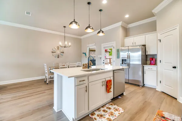 a kitchen that has a lot of white cabinets and stainless steel appliances
