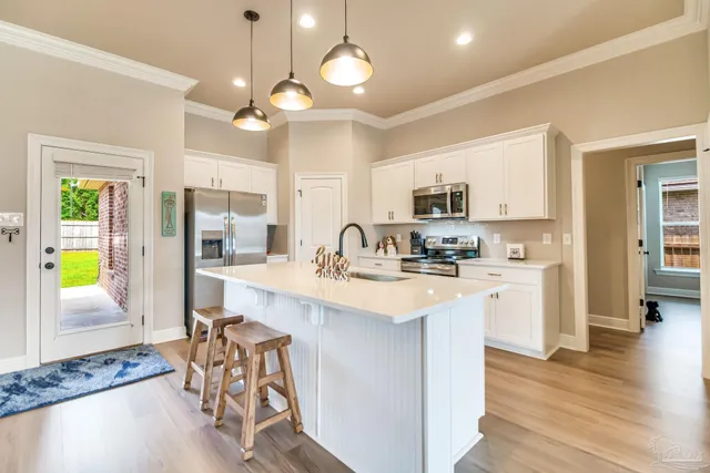 a kitchen with stainless steel appliances granite countertop a stove top oven a refrigerator a sink and dishwasher with wooden floor