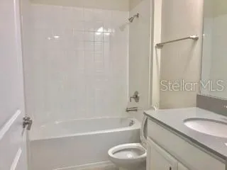 a bathroom with a granite countertop sink a toilet and shower