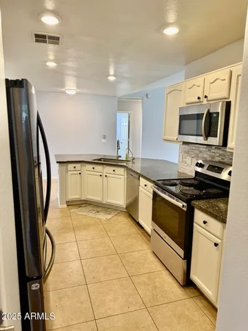 a kitchen with stainless steel appliances granite countertop a refrigerator a stove top oven and a sink