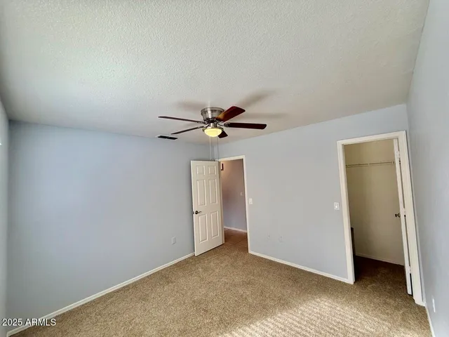 an empty room with a ceiling fan and carpet