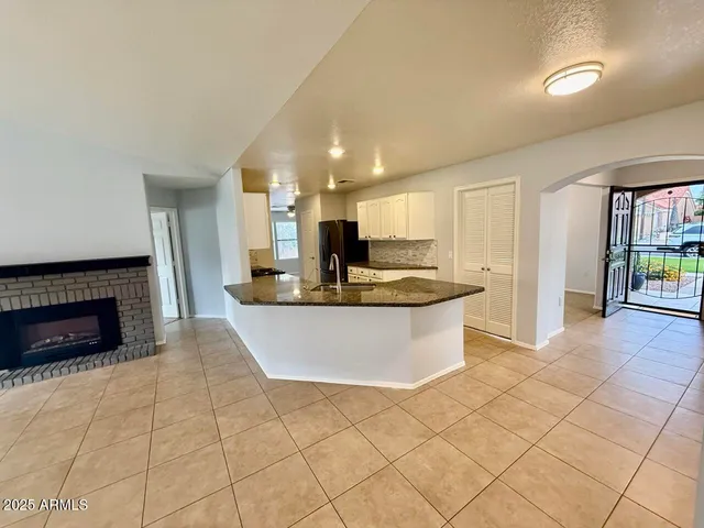a view of kitchen with stainless steel appliances granite countertop a stove a sink a refrigerator white cabinets and couches