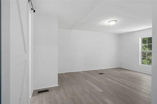 an empty room with wooden floor and windows