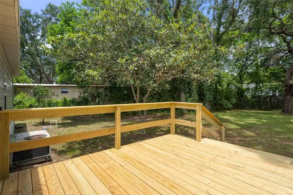 a view of balcony with two large trees and wooden fence