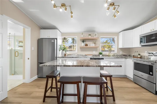 a kitchen with refrigerator a stove and chairs