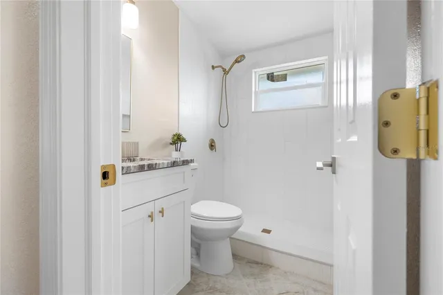 a bathroom with a granite countertop toilet sink and mirror