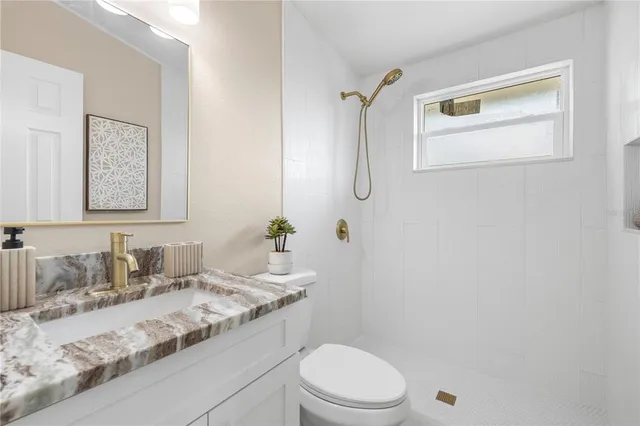 a bathroom with a granite countertop sink a toilet and mirror