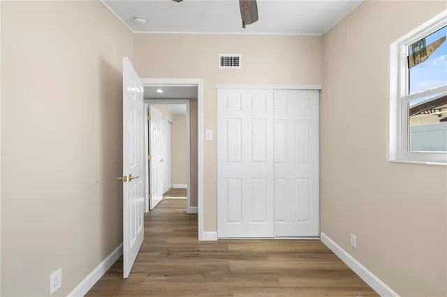a view of an empty room with wooden floor and a window