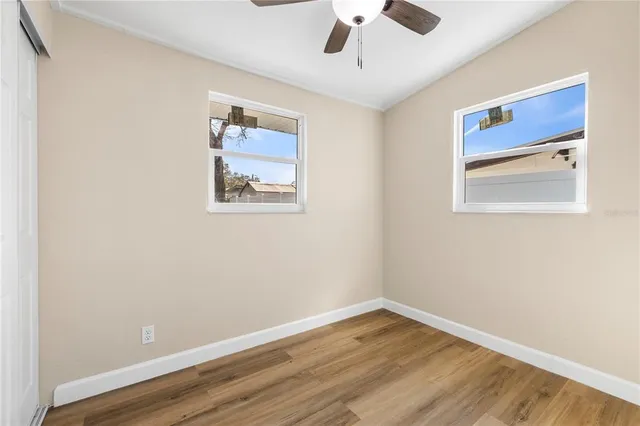 a view of an empty room with wooden floor and a window