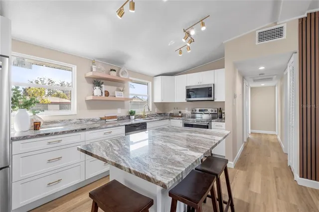a large kitchen with a table chairs refrigerator and microwave