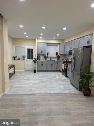 a large kitchen with stainless steel appliances kitchen island granite countertop a refrigerator and a cabinets