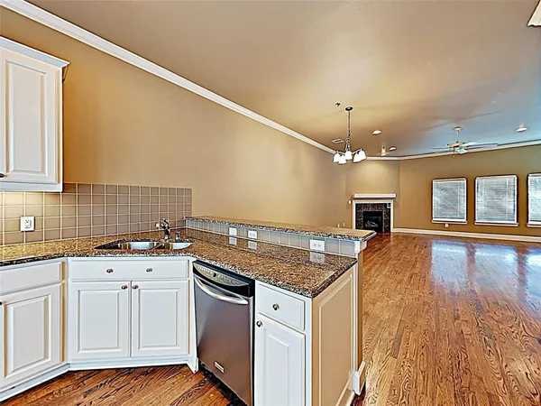 a kitchen with granite countertop a sink cabinets and wooden floor